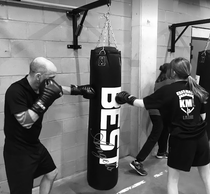 2 élèves frappes dans un sac avec puissance pendant un entrainement technique, en travaillant la précision et l'endurance au club de boxe Rixensart Genval.